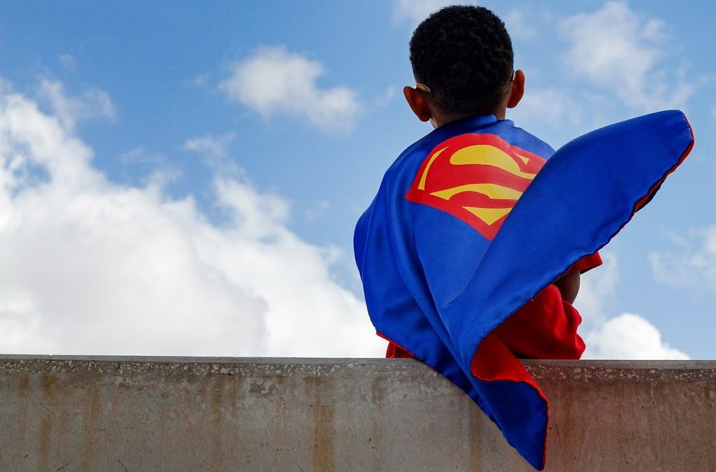 Boy in Superman cape on ledge, adoption fundraiser