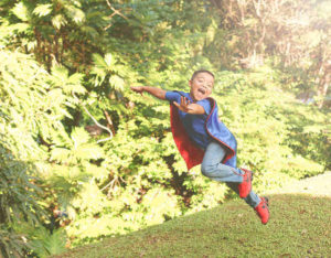 Boy flying in superman cape