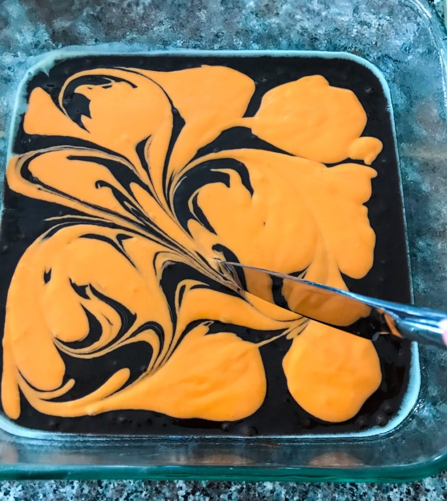 Use butter knife to swirl Halloween cheesecake brownies